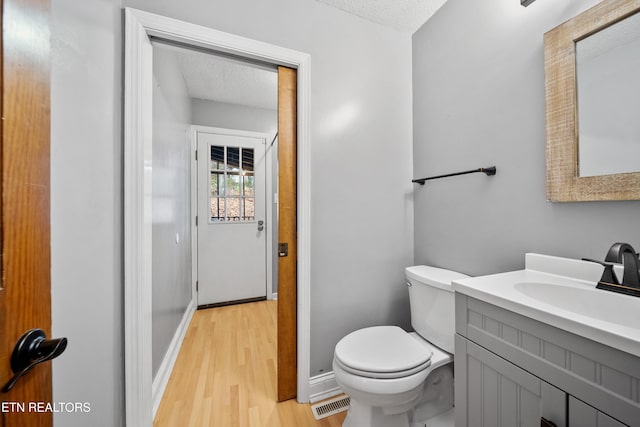 bathroom with vanity, wood-type flooring, toilet, and a textured ceiling