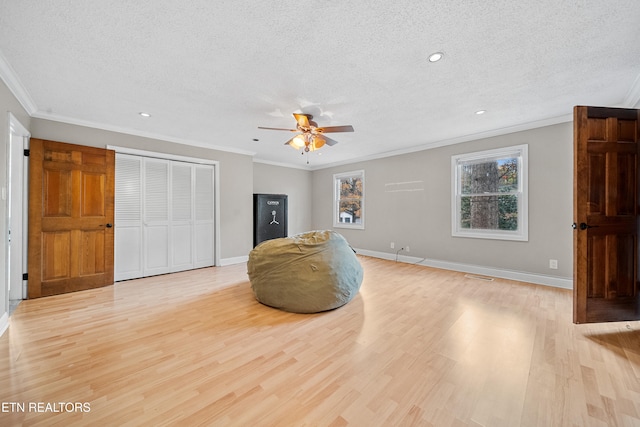 living area featuring ceiling fan, ornamental molding, light hardwood / wood-style floors, and a textured ceiling