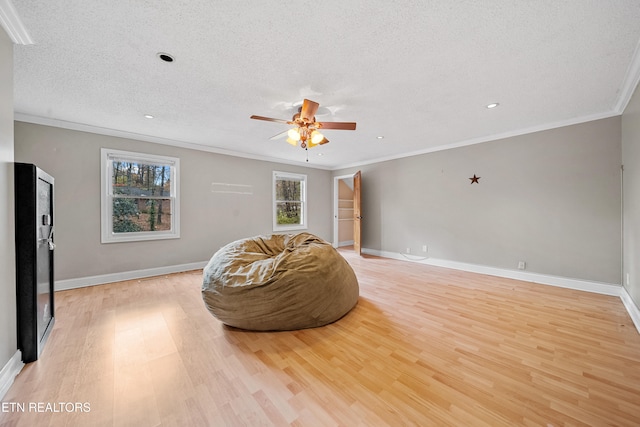 sitting room featuring ceiling fan, light hardwood / wood-style flooring, ornamental molding, and a textured ceiling