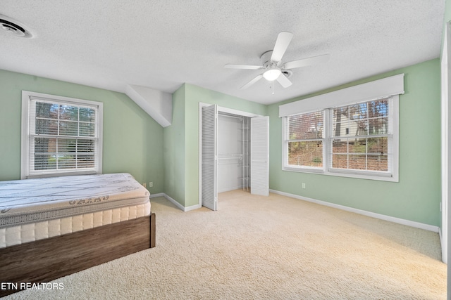 carpeted bedroom featuring ceiling fan, a textured ceiling, and a closet