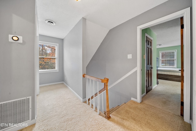 hallway with light carpet and a textured ceiling