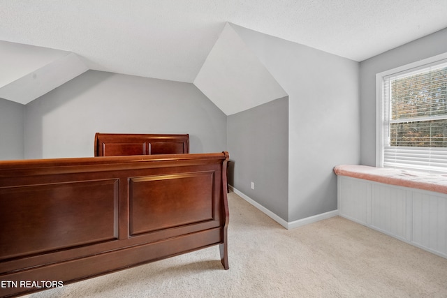 bedroom featuring light colored carpet, lofted ceiling, and a textured ceiling