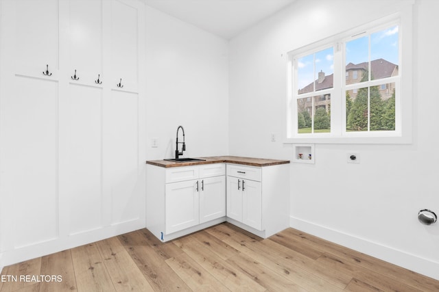 laundry room with electric dryer hookup, cabinets, sink, light hardwood / wood-style flooring, and washer hookup