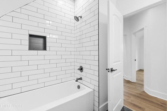 bathroom featuring wood-type flooring and tiled shower / bath