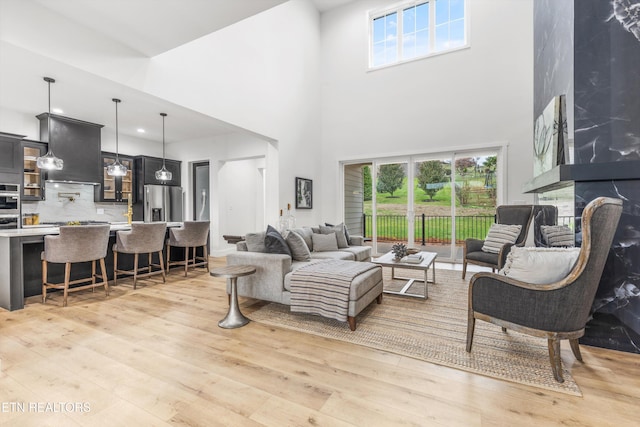 living room featuring a high ceiling, light hardwood / wood-style flooring, and a wealth of natural light