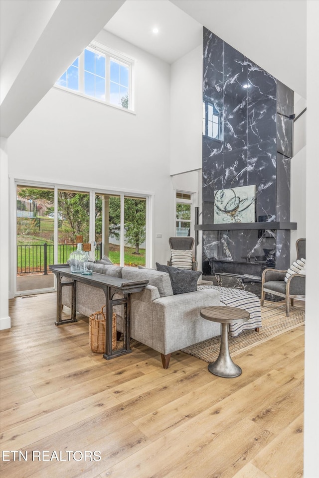 living room with wood-type flooring, a fireplace, and a towering ceiling