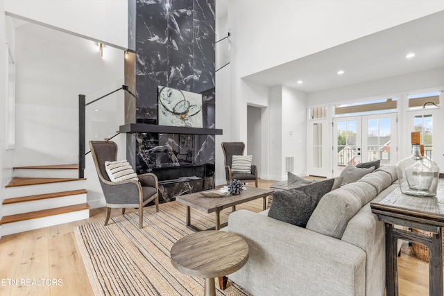 living room with a fireplace, french doors, a high ceiling, and hardwood / wood-style flooring