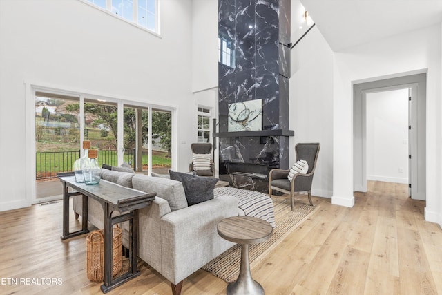 living room featuring a high end fireplace, a towering ceiling, and light hardwood / wood-style flooring