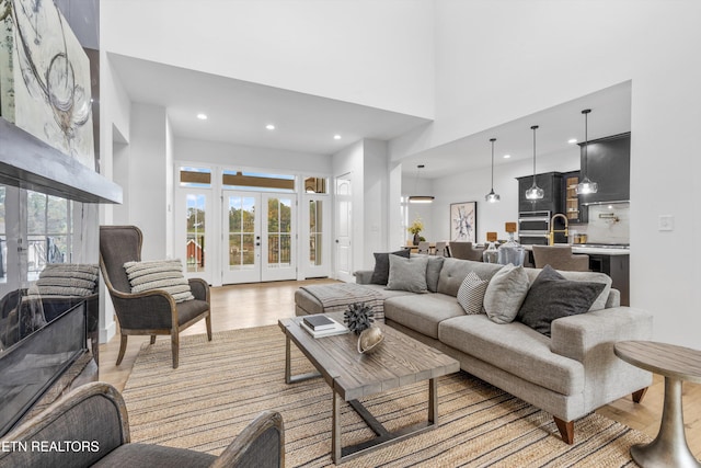 living room with plenty of natural light, light wood-type flooring, and french doors