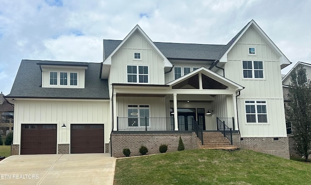 view of front of property featuring a front yard, a garage, and covered porch