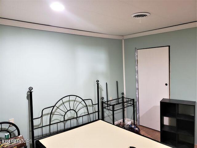 bedroom featuring wood-type flooring and crown molding