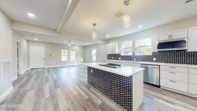 kitchen featuring white cabinets, stainless steel appliances, a wealth of natural light, and hanging light fixtures