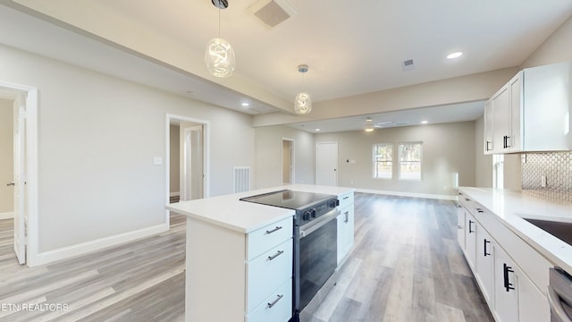 kitchen with appliances with stainless steel finishes, light wood-type flooring, tasteful backsplash, decorative light fixtures, and white cabinets