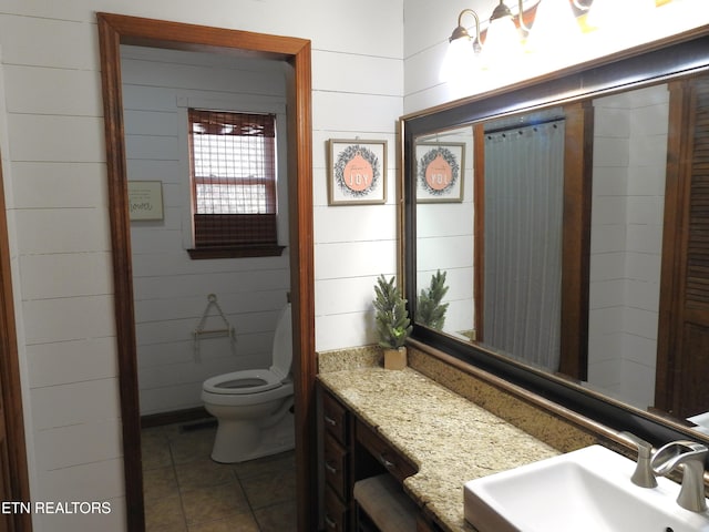 bathroom with tile patterned floors, wood walls, vanity, and toilet