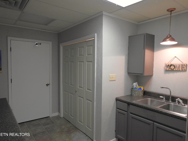 kitchen with a paneled ceiling, sink, gray cabinetry, and decorative light fixtures