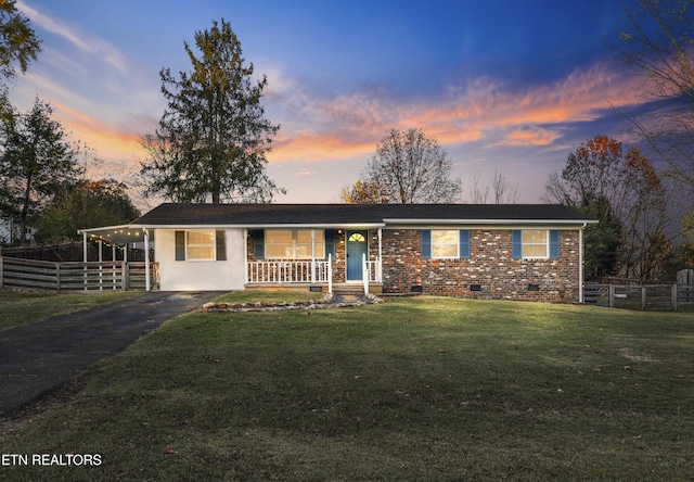 ranch-style house featuring a carport, covered porch, and a yard