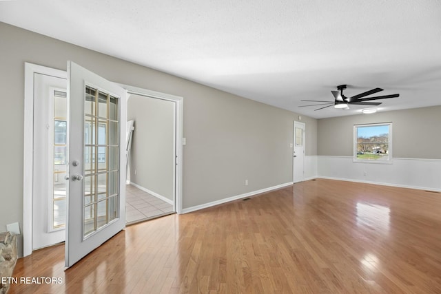 unfurnished room with french doors, a textured ceiling, light hardwood / wood-style flooring, and ceiling fan