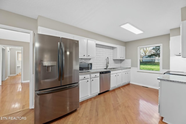 kitchen featuring white cabinets, appliances with stainless steel finishes, light hardwood / wood-style floors, and sink