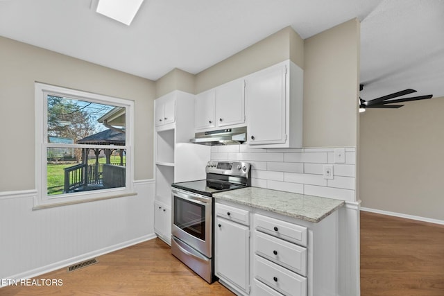 kitchen featuring white cabinets, decorative backsplash, stainless steel range with electric cooktop, and light wood-type flooring