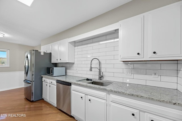 kitchen featuring white cabinets, sink, decorative backsplash, appliances with stainless steel finishes, and light hardwood / wood-style floors