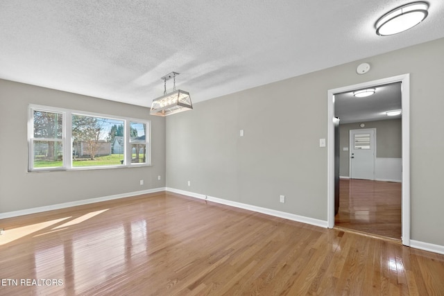 empty room with wood-type flooring and a textured ceiling