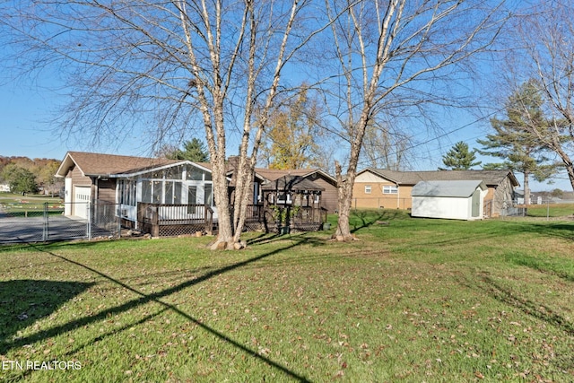 view of yard with a sunroom, a storage unit, and a wooden deck