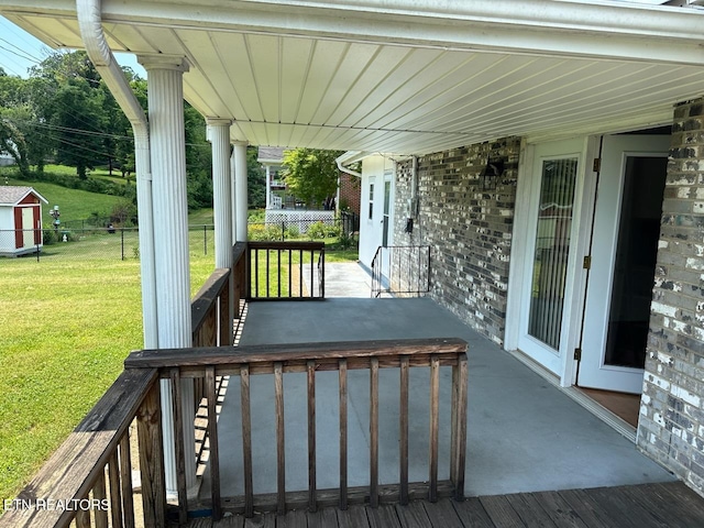 wooden terrace featuring a lawn and covered porch