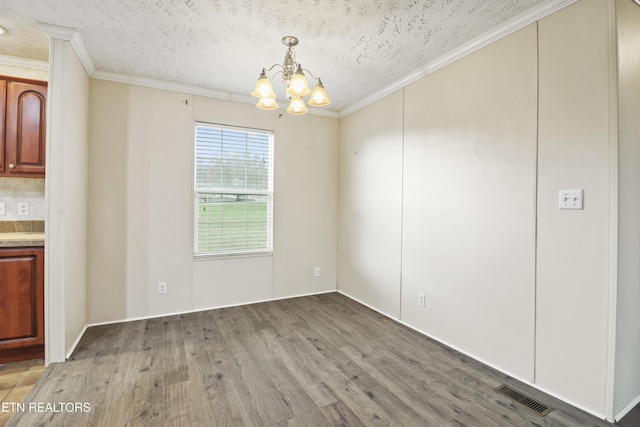 unfurnished dining area featuring crown molding, a chandelier, a textured ceiling, and hardwood / wood-style flooring