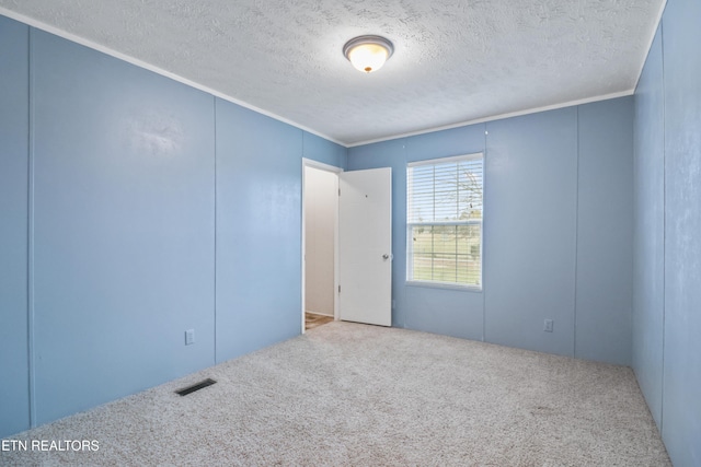 unfurnished room featuring carpet, a textured ceiling, and ornamental molding