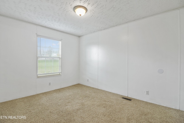 carpeted empty room with a textured ceiling