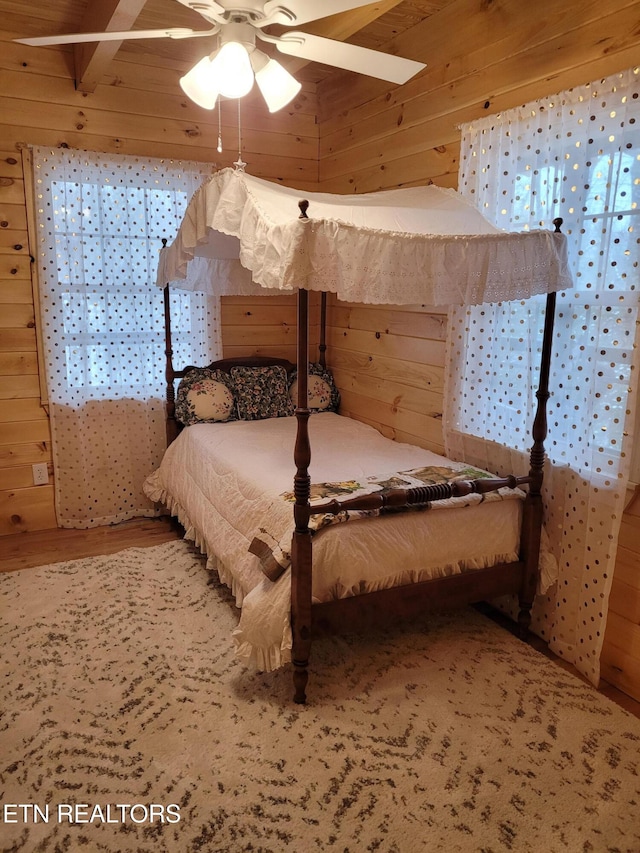 bedroom featuring hardwood / wood-style flooring, ceiling fan, and wooden walls