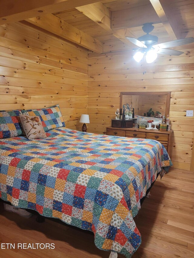 bedroom featuring wooden walls, hardwood / wood-style floors, and beam ceiling