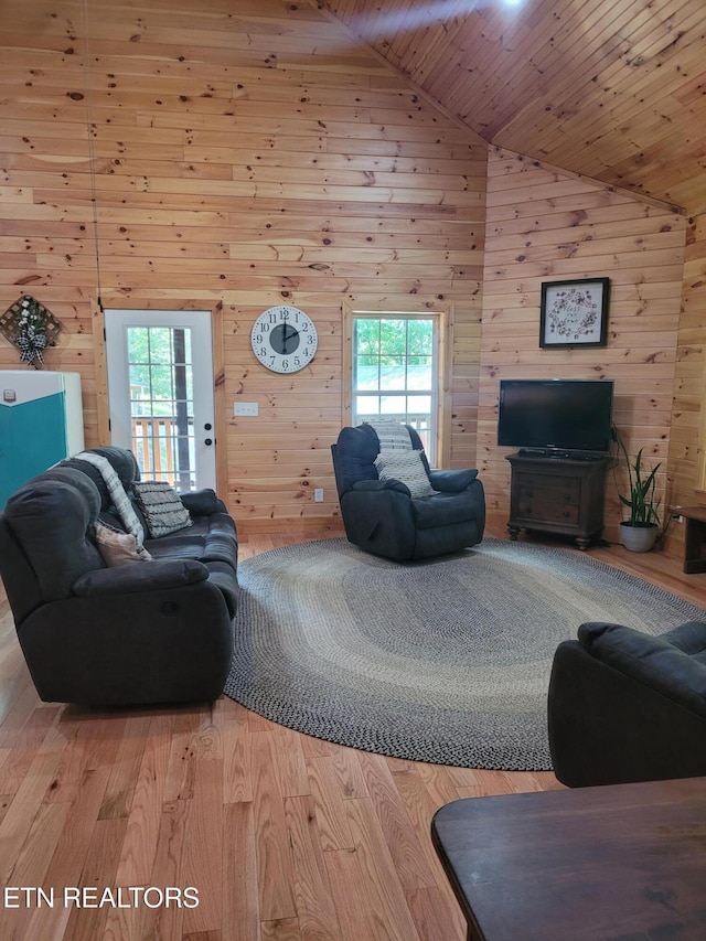 living room with high vaulted ceiling, wooden ceiling, wooden walls, and light hardwood / wood-style flooring