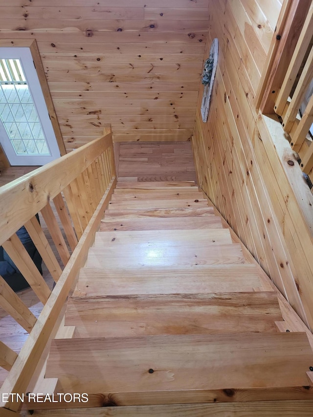 stairs featuring wooden walls and wood-type flooring