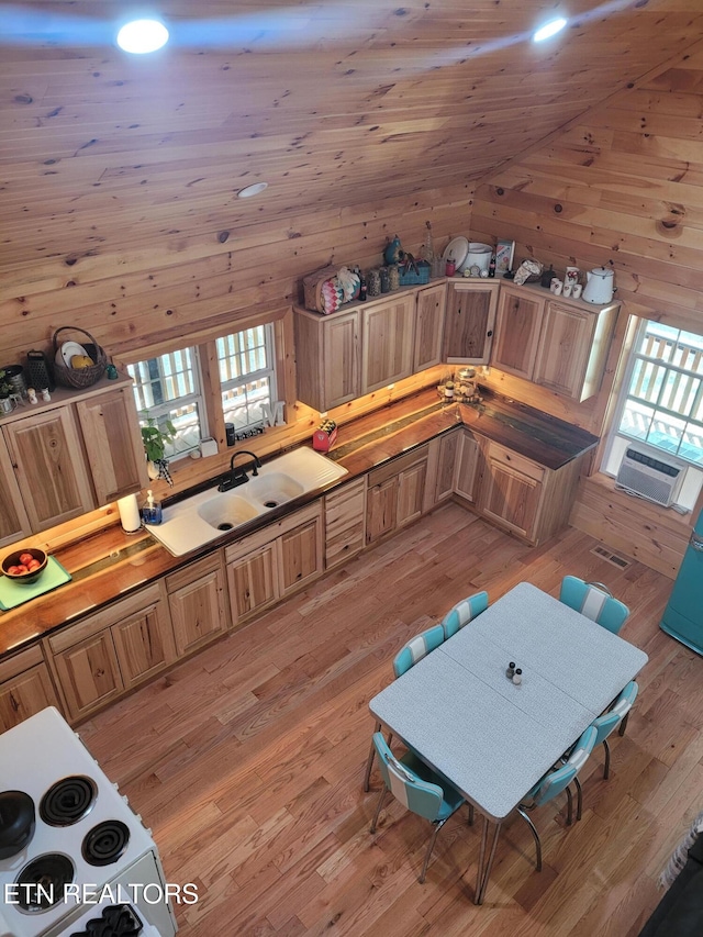 interior space with light wood-type flooring, cooling unit, vaulted ceiling, and wood walls