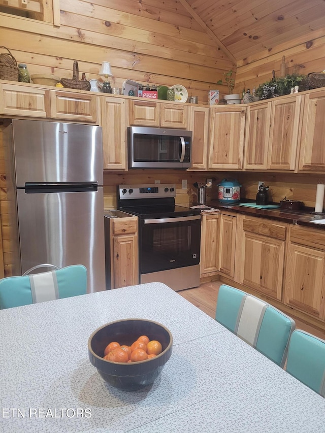 kitchen featuring lofted ceiling, wood walls, wood ceiling, appliances with stainless steel finishes, and light hardwood / wood-style floors