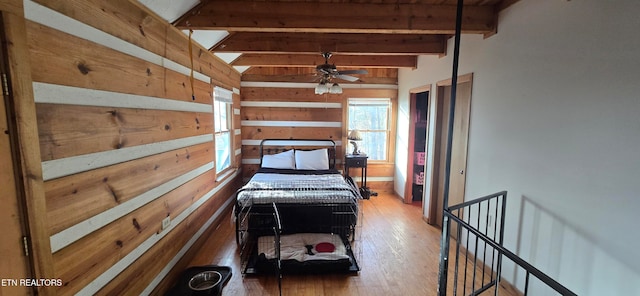 bedroom with beamed ceiling, wood-type flooring, and wood walls