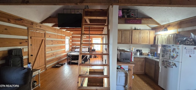 kitchen with wood walls, white fridge, and wood-type flooring