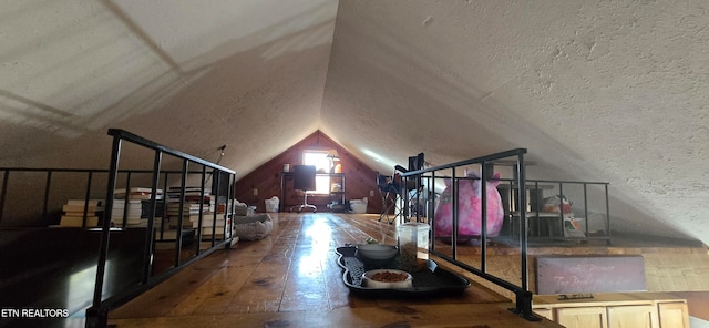 additional living space with lofted ceiling, a textured ceiling, and hardwood / wood-style flooring