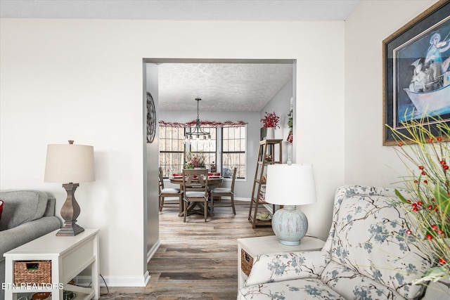 living area featuring hardwood / wood-style floors, a textured ceiling, and an inviting chandelier