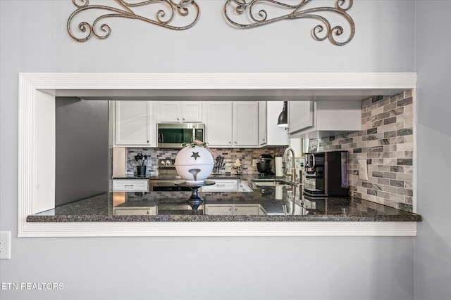 kitchen with white cabinetry, dark stone countertops, decorative backsplash, and sink