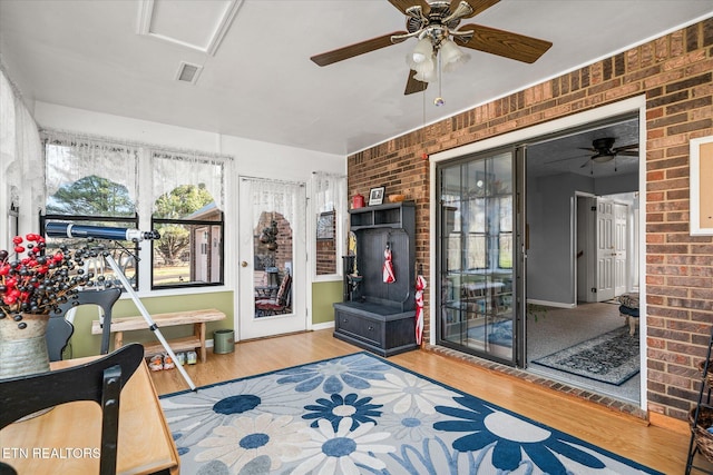 interior space with hardwood / wood-style flooring, ceiling fan, and brick wall