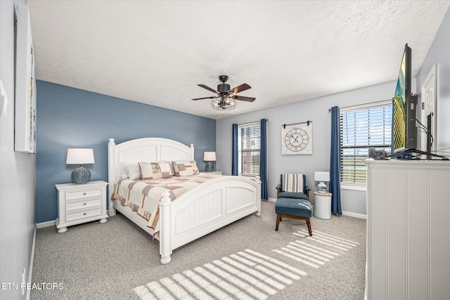 bedroom with ceiling fan, carpet floors, and a textured ceiling