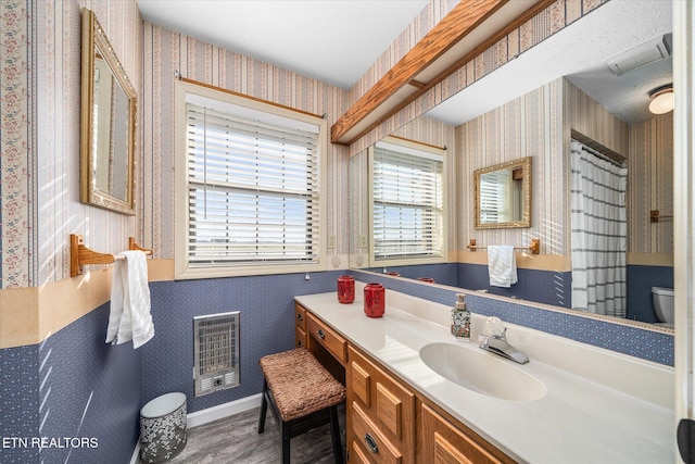 bathroom with wood-type flooring, vanity, heating unit, and toilet