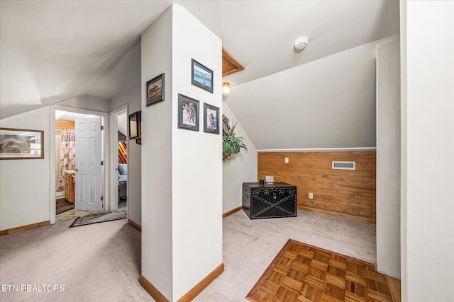 additional living space with light parquet flooring, vaulted ceiling, and wood walls