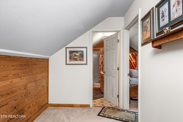 interior space with light colored carpet, lofted ceiling, and wood walls