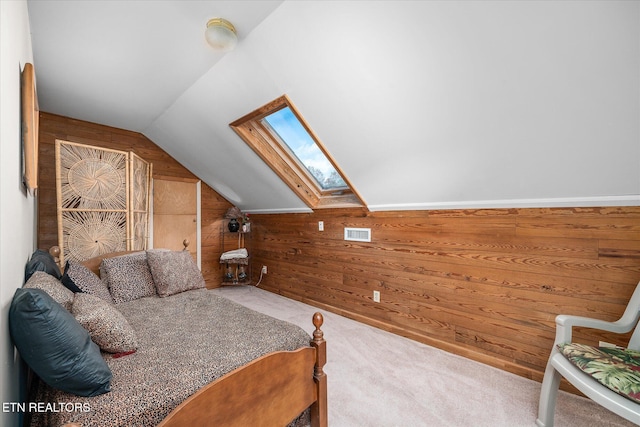 bedroom with carpet, wooden walls, and vaulted ceiling with skylight