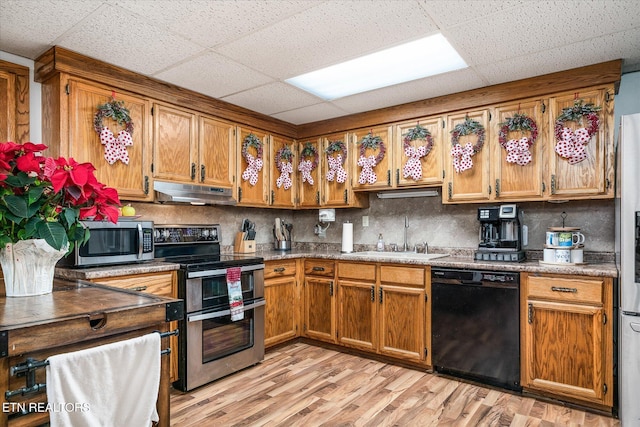 kitchen with stainless steel appliances, light hardwood / wood-style flooring, a drop ceiling, and sink