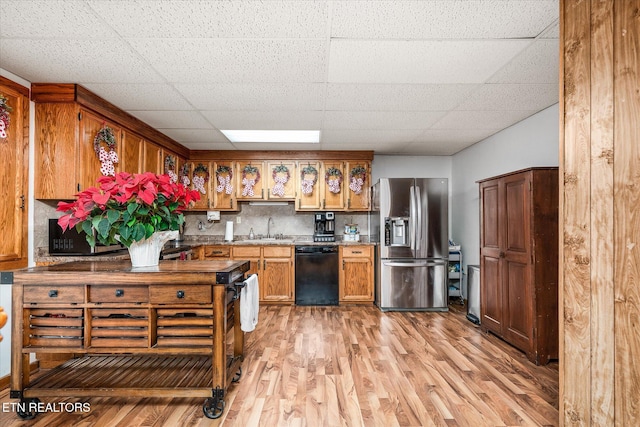 kitchen with stainless steel fridge, light wood-type flooring, backsplash, sink, and black dishwasher