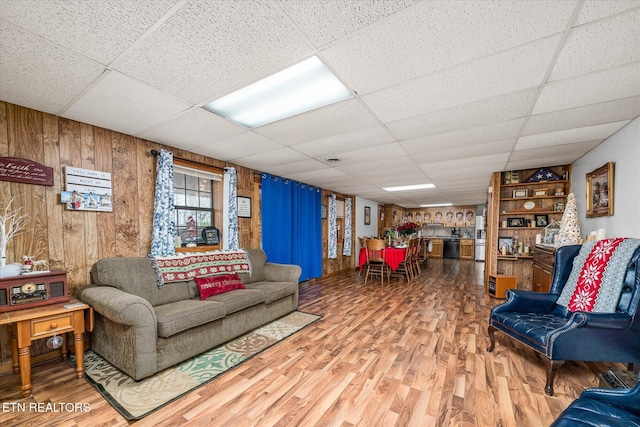 living room with a paneled ceiling, wooden walls, and hardwood / wood-style flooring